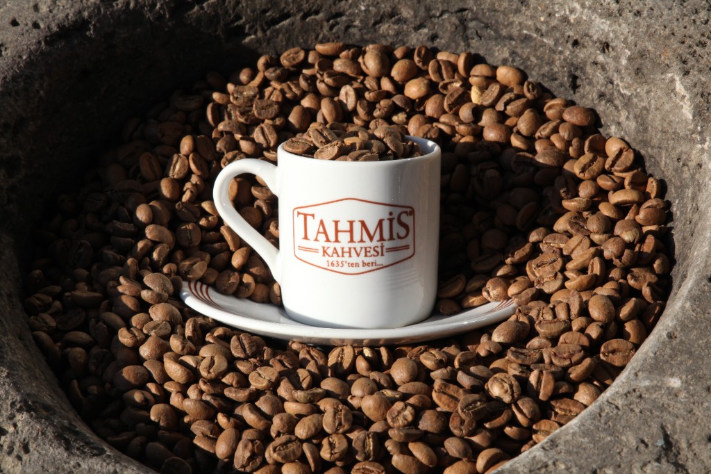 Tahmis Kahvesi cup in a traditional stone mortar filled with roasted coffee beans